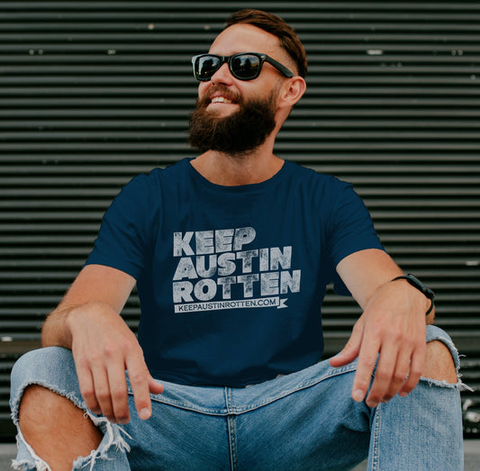 Man wearing sunglasses and a 'Keep Austin Rotten' t-shirt sitting on a step.